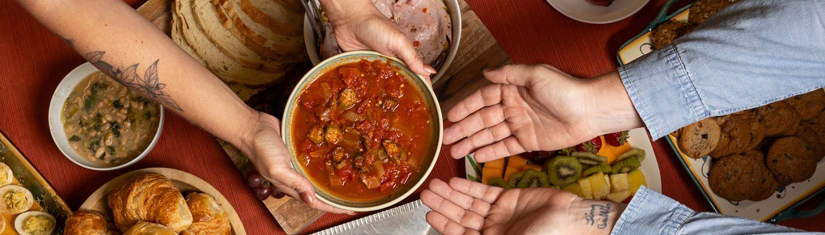 Hands passing a dish during holiday meal.