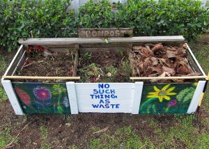 A horizonal view of a Photo of compost in three bins with a sign that says No such thing as waste UFIFAS Cat Wofford