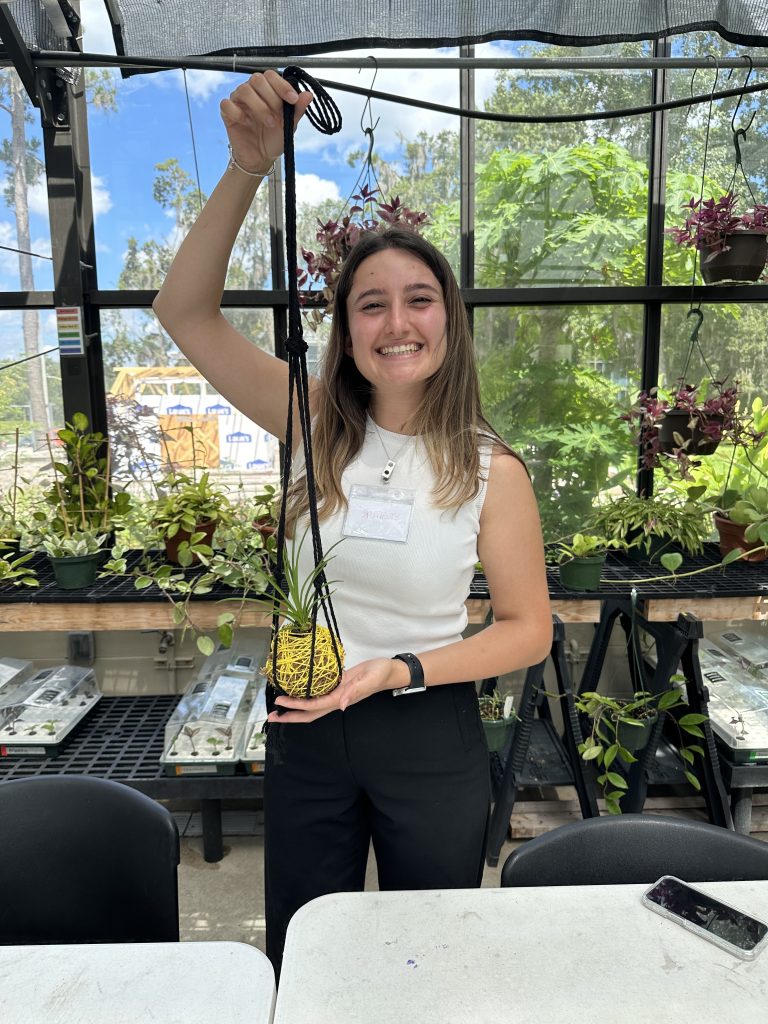 Yagmur Unal showing the kokedama (Japanese moss ball) and macrame hanger that she created. Photo: UF/IFAS, Brooke Meadows