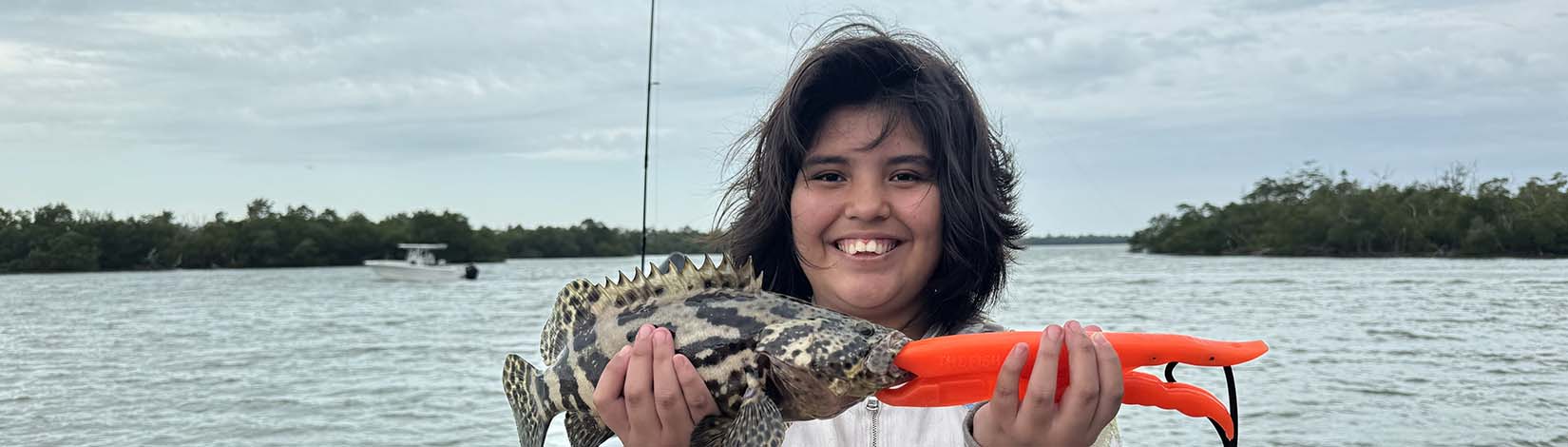 girl with fish she caught as part of a fishing class on the water blog banner