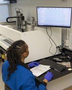 A man in a lab coat sits at a computer to run a soil pH test.
