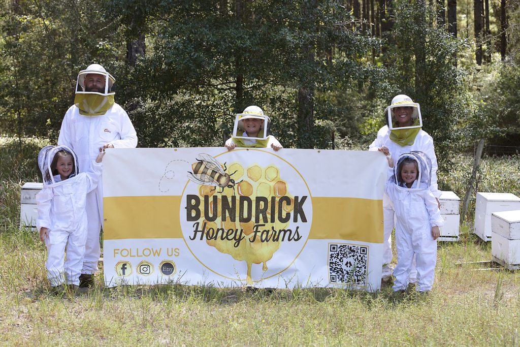 Tomlin Family in bee suits with farm sign