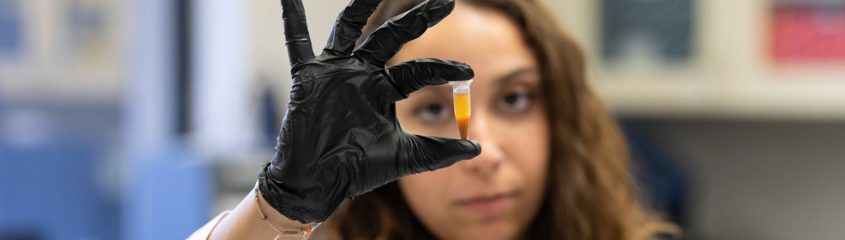 A woman holding a a vial in a research lab.
