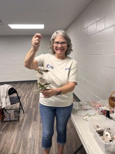 Woman smiling holding up a plant vog she made 