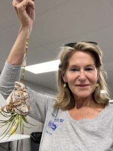 a selfie of a Woman smiling holding up a plant vog she made 