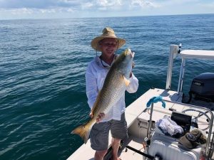 man holding larger redfish on a boat.