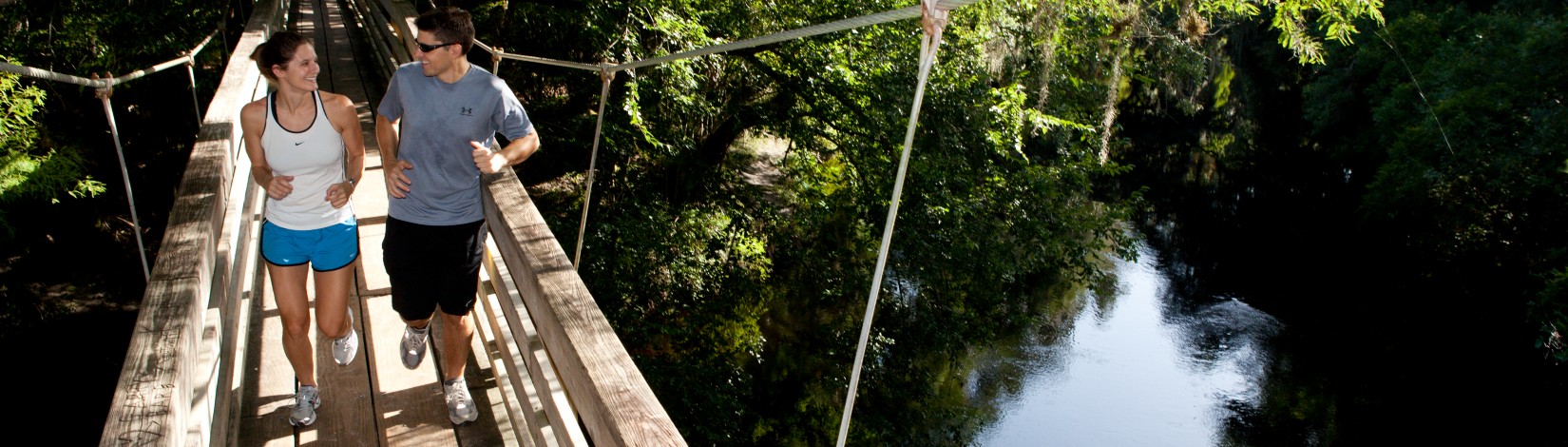 Two runners crossing a bridge over the Hillsborough River in Hillsborough River State Park. Florida parks and recreation, leisure, outdoor activities, fitness.