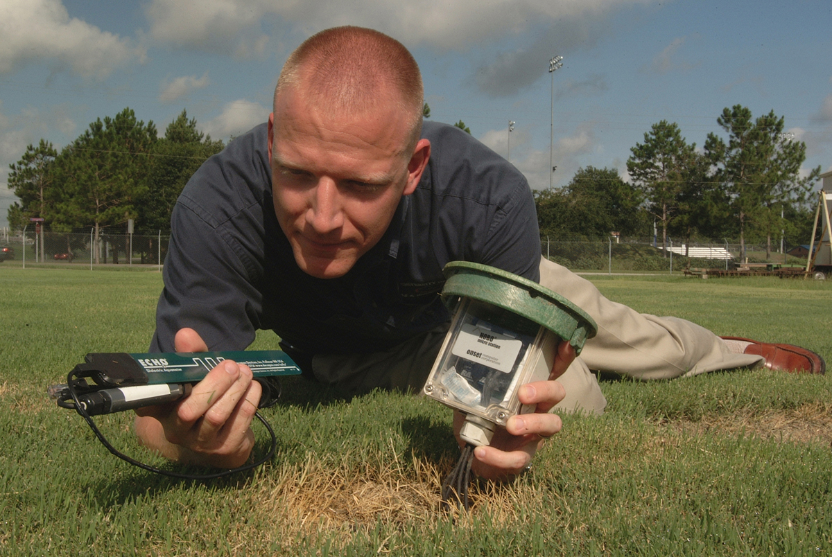 Michael Dukes, an assistant professor with the University of Florida's Institute of Food and Agricultural Sciences in Gainesville, holds equipment that measures soil moisture in a turfgrass research plot -- Thursday, July 21, 2005. He says automatic sprinkler systems equipped with soil moisture monitors use 56 percent less water on average than systems with no water-saving devices. The monitors detect moisture in the soil and control the operation of sprinkler systems. (AP photo by Josh Wickham/University of Florida/IFAS)