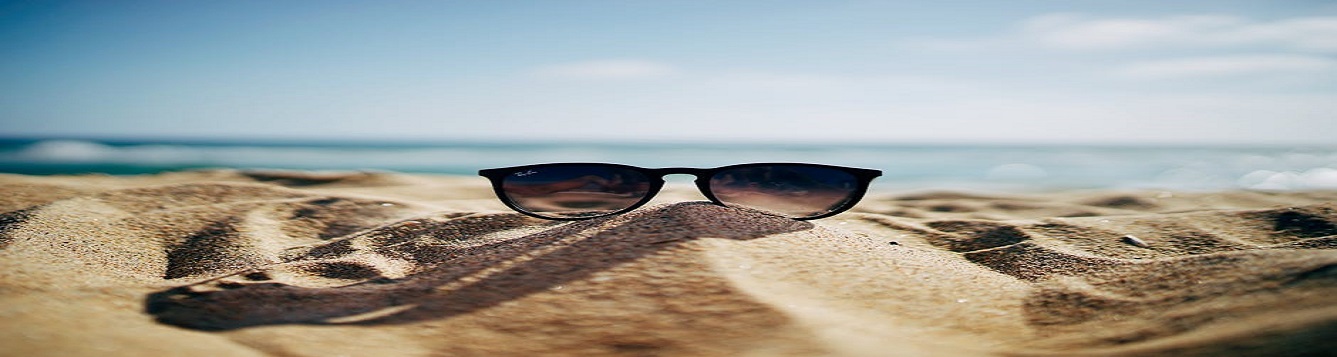 Pair of sunglasses on the sand at the beach