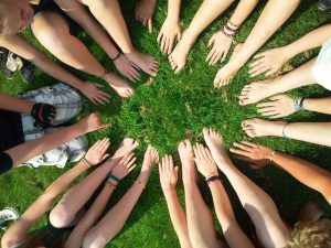 Group of people all putting their hands into a circle in a field