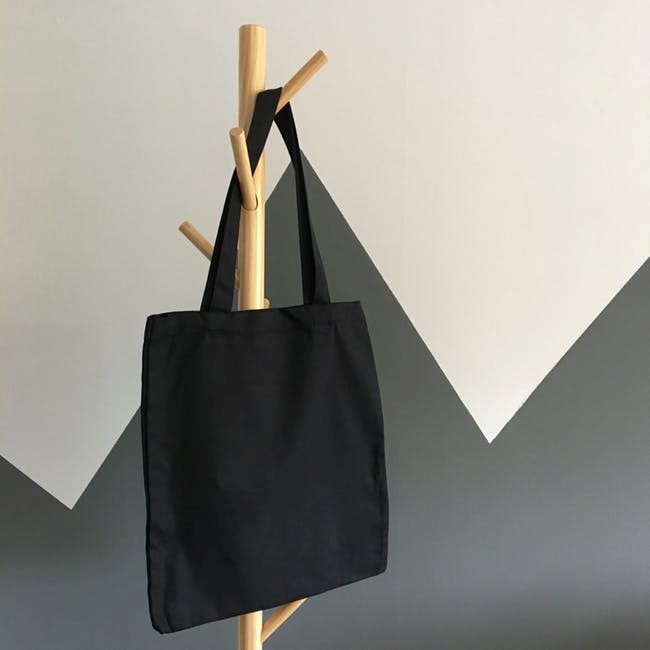 A black reusable bag hanging on a coat hanger. 