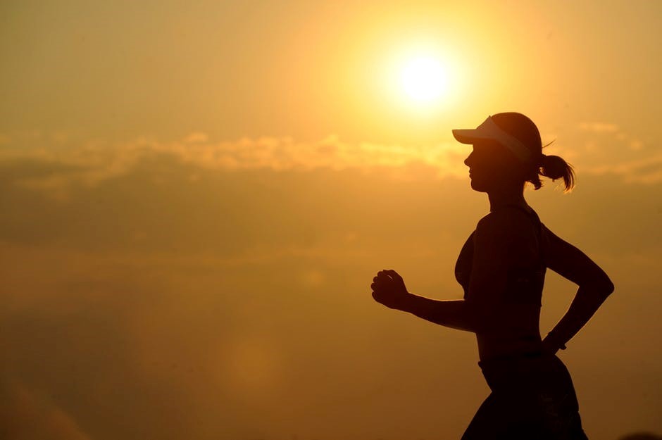 Woman jogging with the sun in the background.