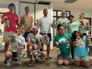 Group of adults and one young child holding up vertical oyster gardens they just built.
