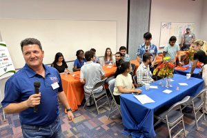 ozgur batuman holding microphone in front of crowded room