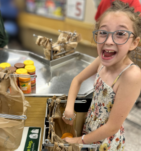 Young girl bagging peanut butter jars at grocery store