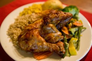 A complete chicken dinner with rice, corn, bread, and steamed vegetables.