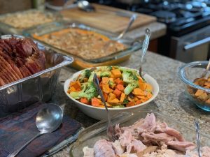 multiple thanksgiving dishes with a bowl of vegetables highlighted in the middle