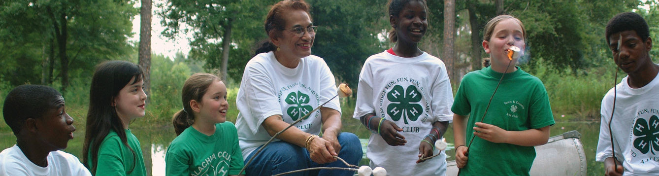 4-H youth enjoy s'mores at a campfire with an adult leader.