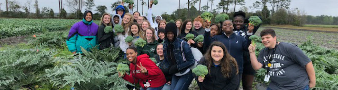 students posing as a group with their harvested vegetables