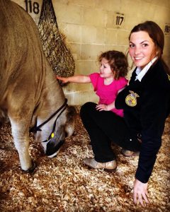 teenage girl with toddler petting cow