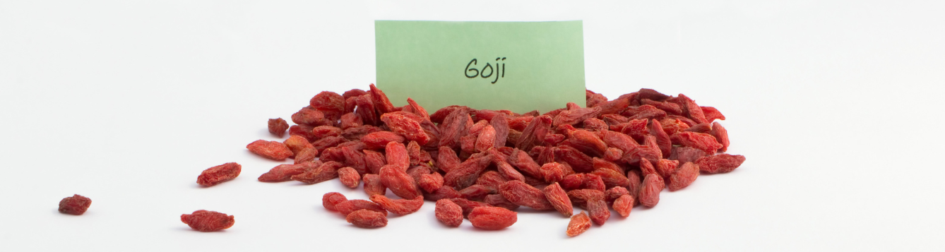 Heap of goji seeds isolated on white background. With green describing label.