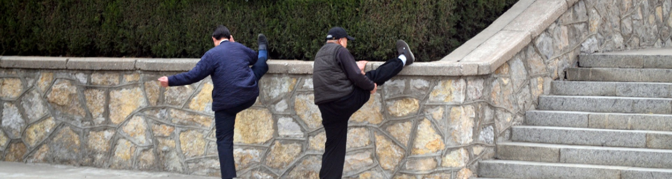 two gentlemen stretch out along a city wall
