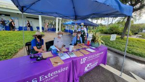 Master Gardener Volunteers staff a check-in table on a rainy Saturday during the group's 2021 plant sale.. [CREDIT: UF/IFAS Extension Sarsaota County]