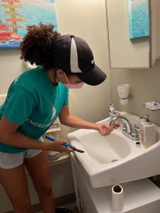 Sustainability staff member installing a low-flow faucet aerator on a low-income resident's bathroom sink at Sarasota Housing Authority.