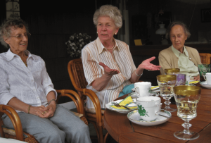 three older adult women share stories and smiles, seated at a table for a tea party. [credit: pixabay.com, assy]