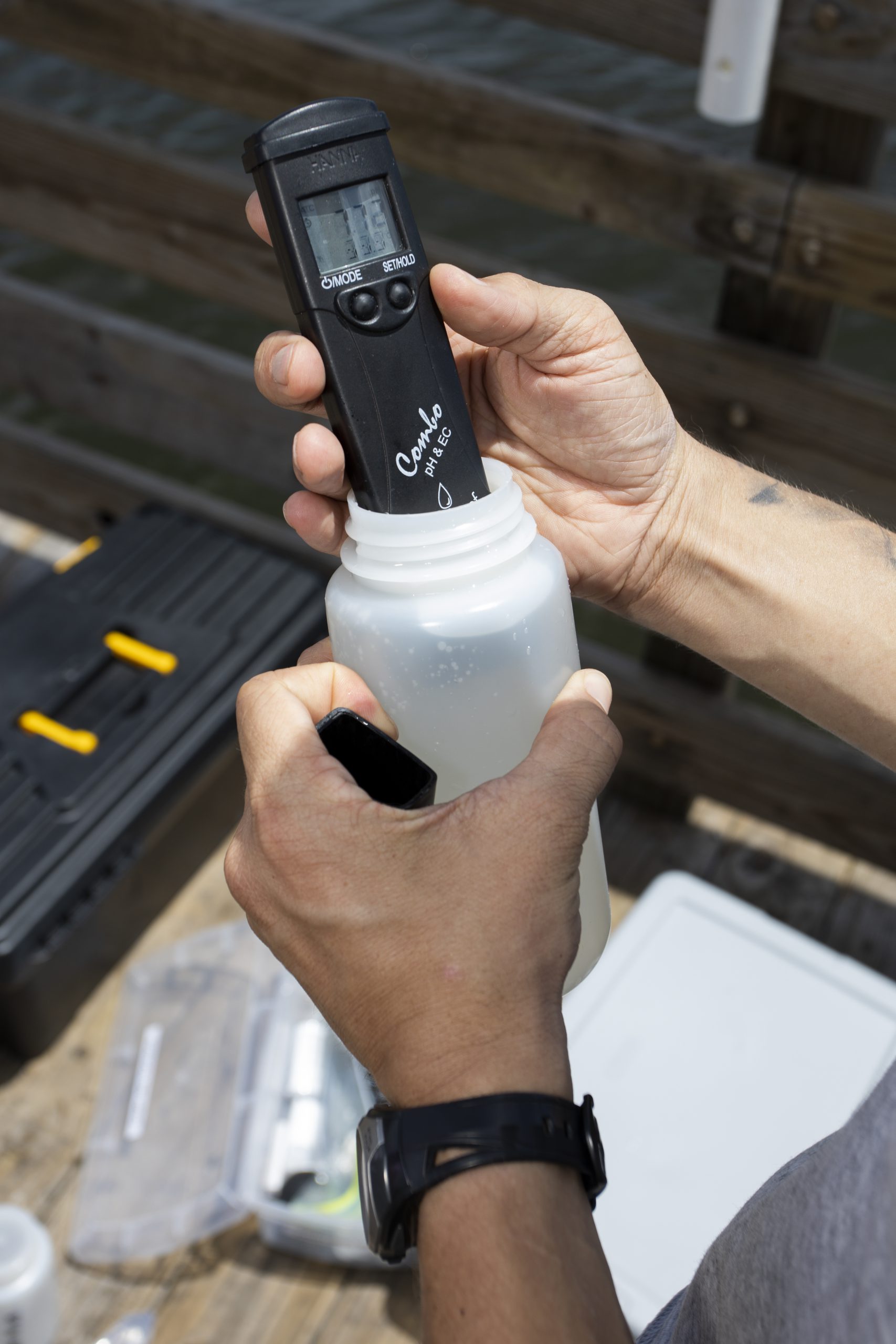 Photo of handheld field meter being used to measure analyze water sample.