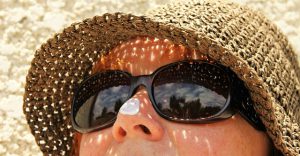 Image of a person in a sunhat and sunglasses with sunscreen on their nose