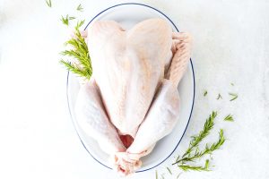 an uncooked, thawed turkey sits on a platter, awaiting cooking. [credit: unsplash.com, hayley ryczek]