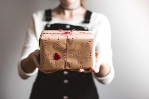 a person holds a personally wrapped holiday gift in two hands, sharing it to the viewer. [credit: unsplash.com, Kira auf der Heide]