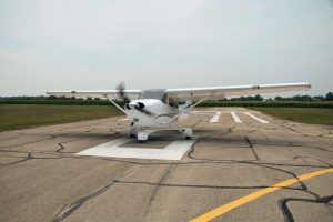 a small, white, single-propeller plane taxis on an airport runway. [credit: unsplash.com, brendan sapp]
