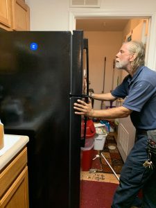 A maintenance working installing a high efficiency ENERGY STAR certified refrigerator at an affordable housing unit.