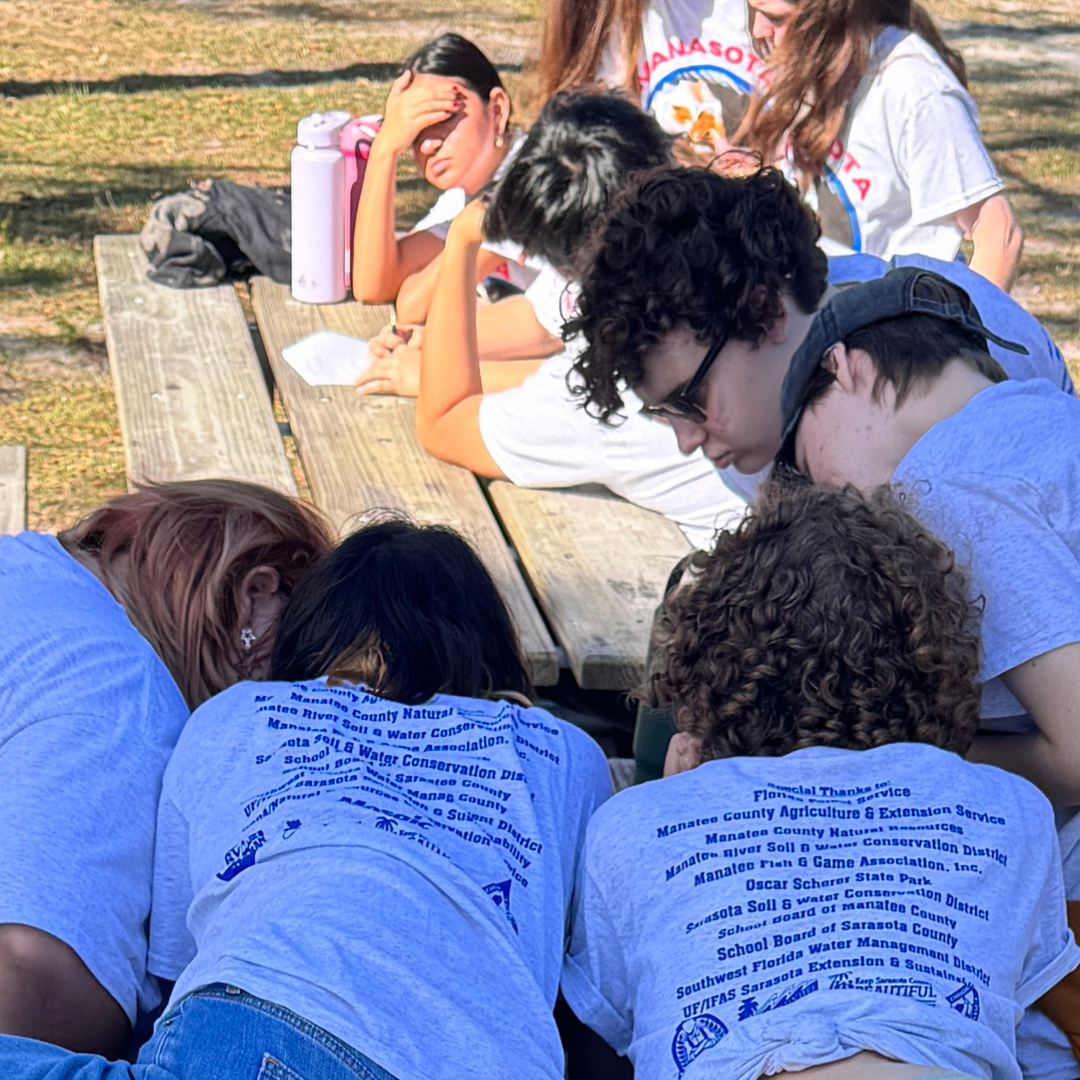 Students sitting at a picnic table gathered around a paper test