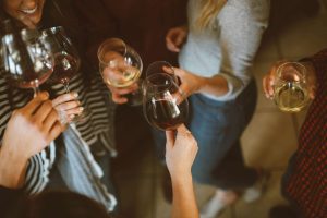 group shot showing multiple people holding long-stemmed wine glasses, with closeup on glasses. [credit: unsplash.com, Kelsey Chance]