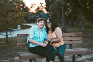 two women sitting side-by-side on a park bench share a laugh. [credit: unsplash.com, dario valenzuela]