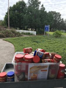 Jars of peanut butter collected during the 2020 UF Peanut Butter Challenge sit on top of a cart outside Sarasota County Extension, on ready for delivery to a local food bank. [CREDIT: UF/IFAS Extension Sarasota County]