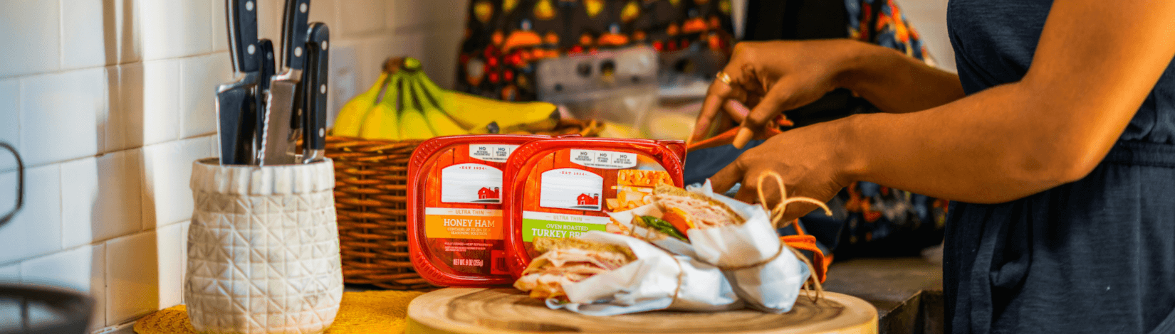 a woman prepares sandwiches at a kitchen countertop. [credit: unsplash.com, hillshire farm]