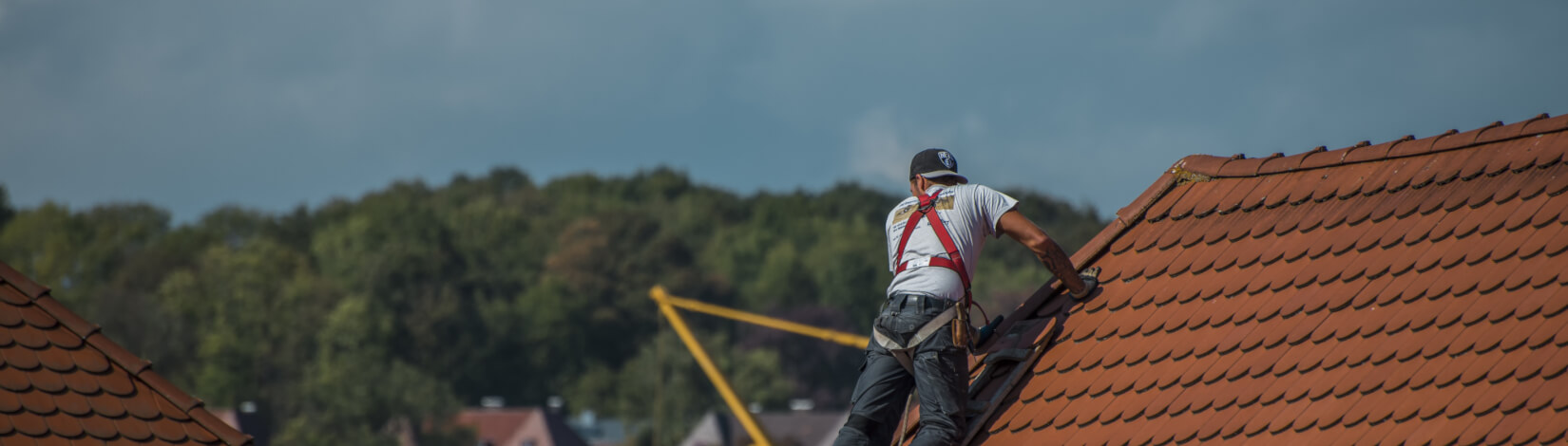 A single worker attempts repairs/upgrades on a red, tile roof. [CREDIT: pixabay.com, Mario Ohibsky]