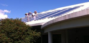 Workers installing solar panels on a roof.