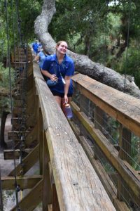 uf/ifas extension sarasota county intern kate albertus walks across a tree canopy "bridge" at myakka river state park during a summer youth camp outing. [credit: uf/ifas extension sarasota county]
