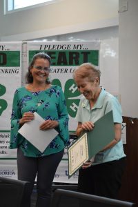 4-H Agent hands Barbara Briggs her volunteer certificate.