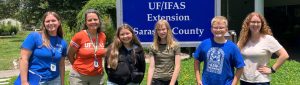 Participants and Sarasota County staff stand in front of the Sarasota County Extension sign, before leaving for iLEAD.