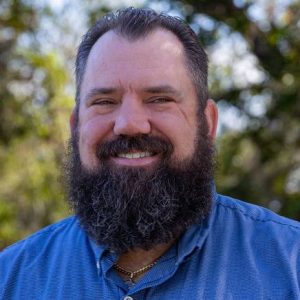 A man known as Steve Kagy stands smiling for a headshot.