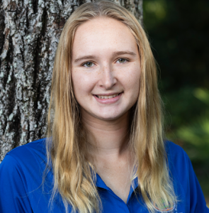 Hailey smiles in front of a tree for her ambassador headshot. 