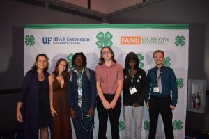 People smile for a picture in front of 4-H backdrop.