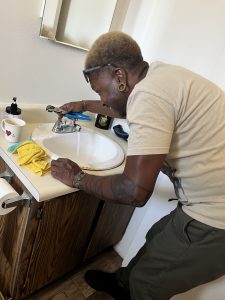 Smiling man holding a wrench turns on the water at a bathroom sink to test a new aerator.
