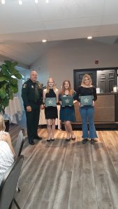 4-H'ers stand with an officer to accept their awards. 